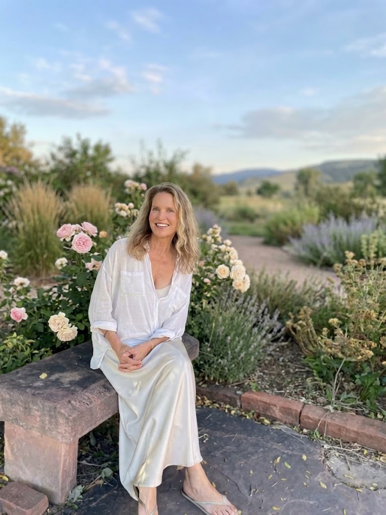 Cynthia Sass, seated on a stone bench among garden roses under a soft evening sky